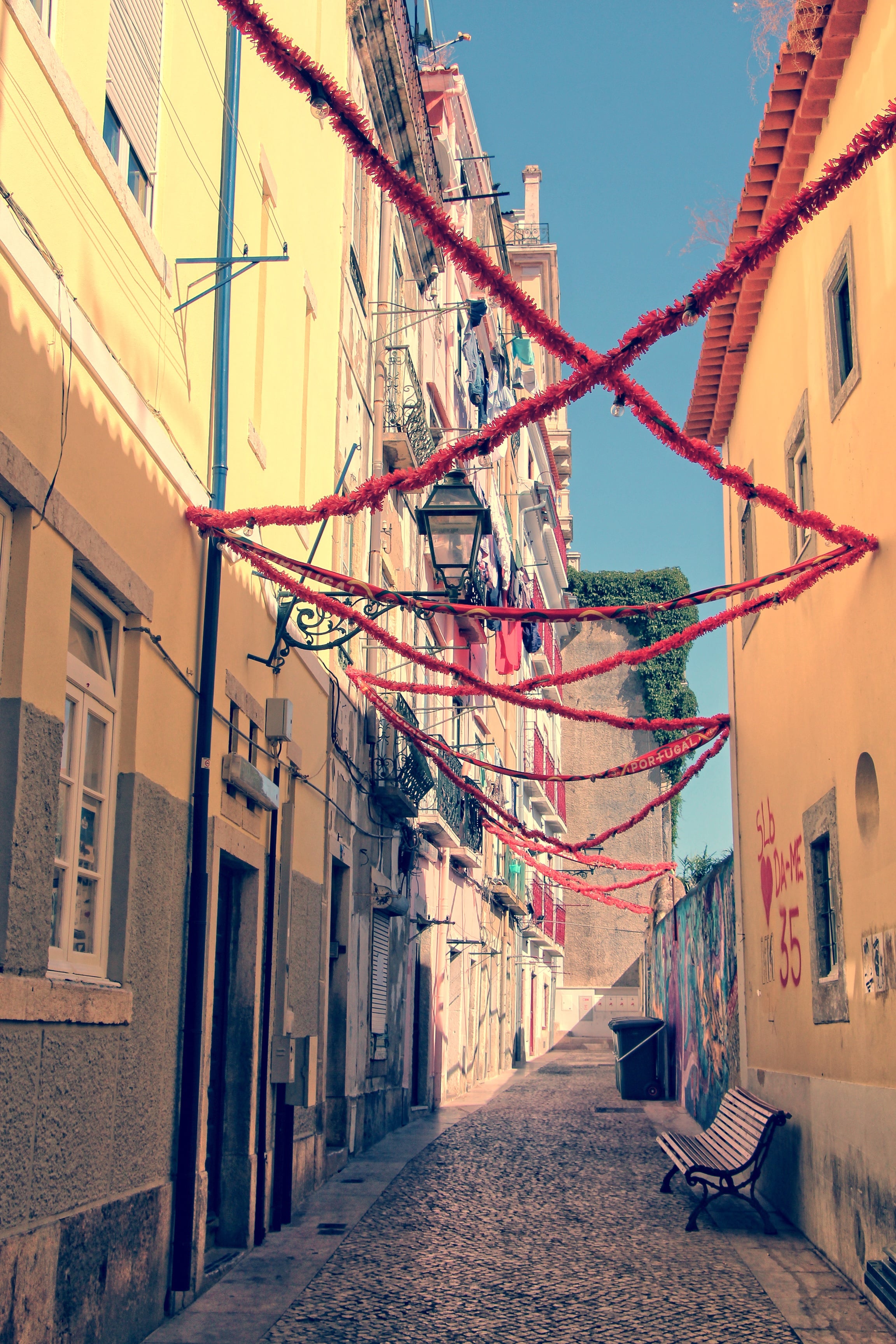 Narrow street in Lisbon with colorful decorations and sunlight